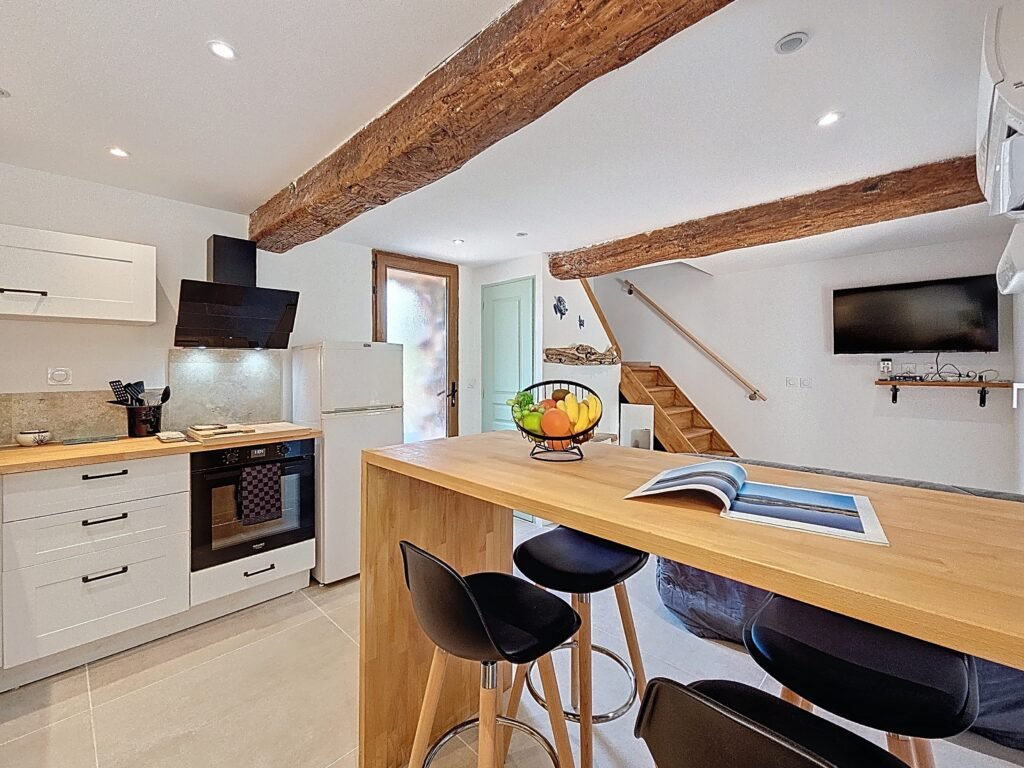 Coin repas lumineux revue ouverte & corbeille de fruits, poutres apparentes four et hotte en arrière plan